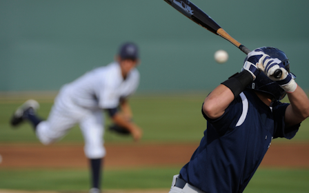A baseball player hitting a ball with a bat.