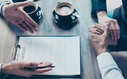 A group of people sitting at a table looking at a paper.