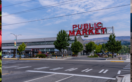 A road with a sign and a building in the background.