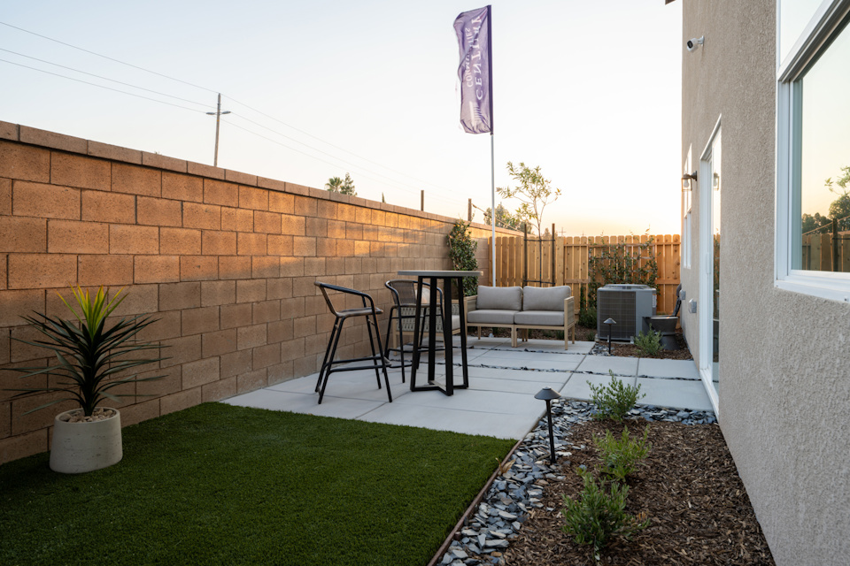 A backyard with a brick wall and a table and chairs.