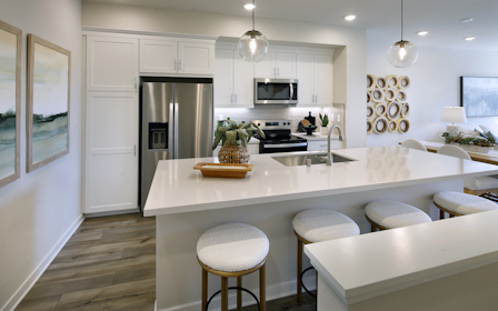 A kitchen with a bar stool and a white counter top.