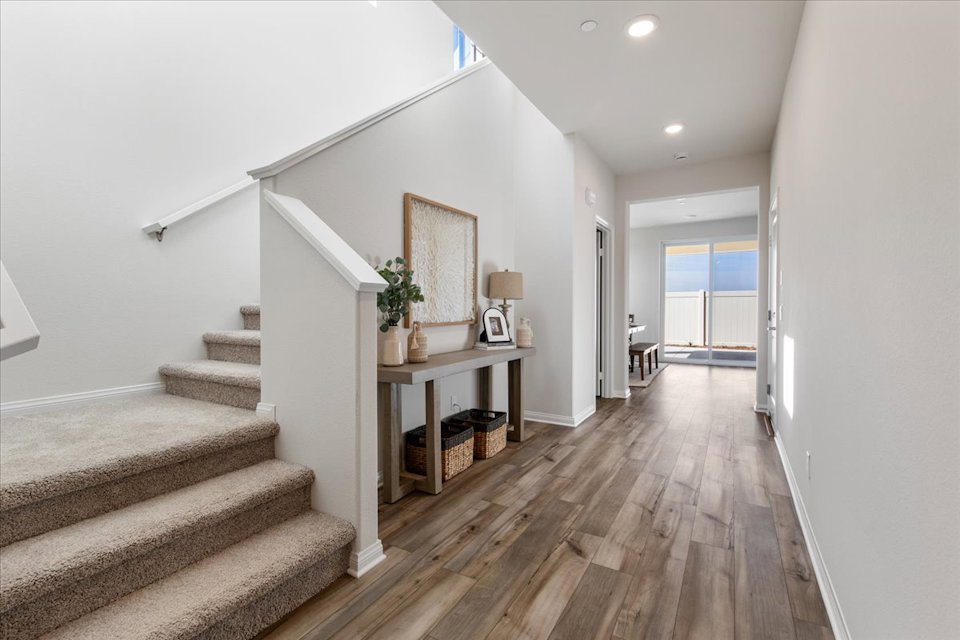 A room with a wood floor and a wood floor with a table and a chair and a rug.