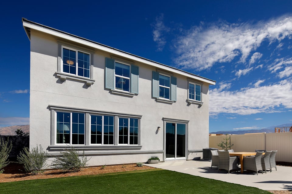 A white house with a lawn and chairs in front of it.