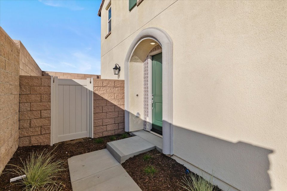 A white building with a door and a stone walkway.
