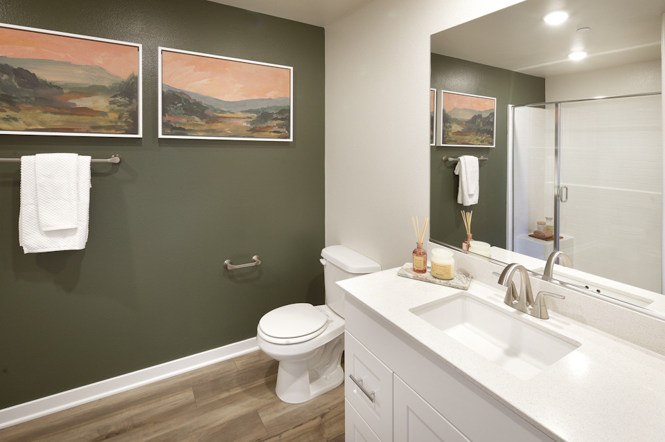 A bathroom with a sink toilet and a mirror.