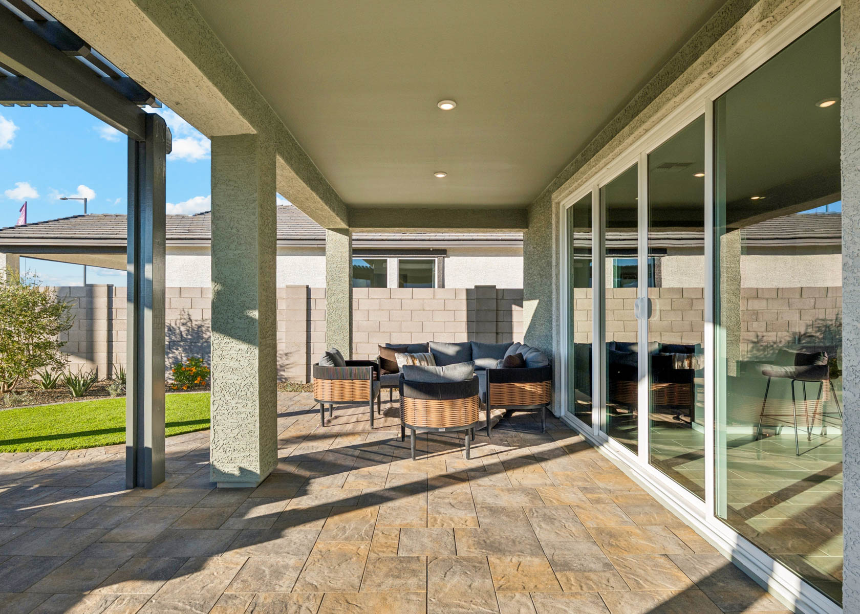A patio with a glass door and a patio with chairs and a table.