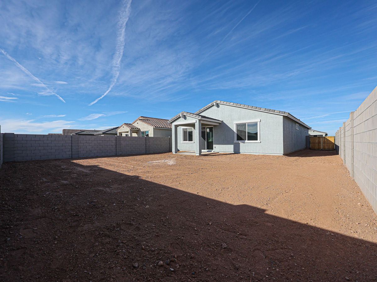 A dirt field with a row of houses in the background.