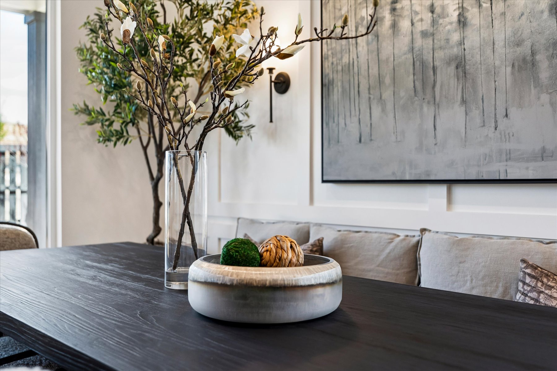 A table with a plant and a vase with fruit on it.