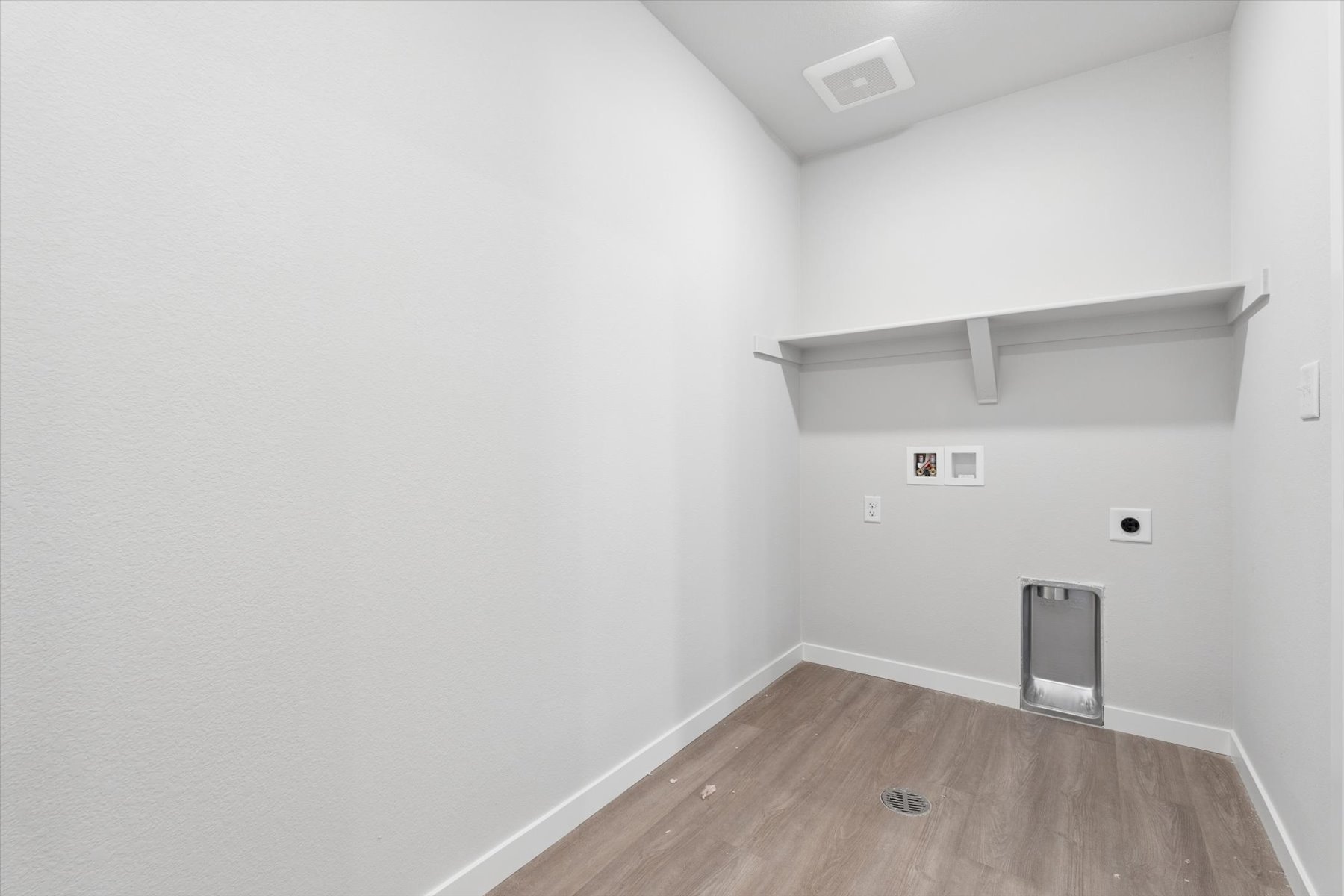 A room with a wood floor and a shelf with a speaker.