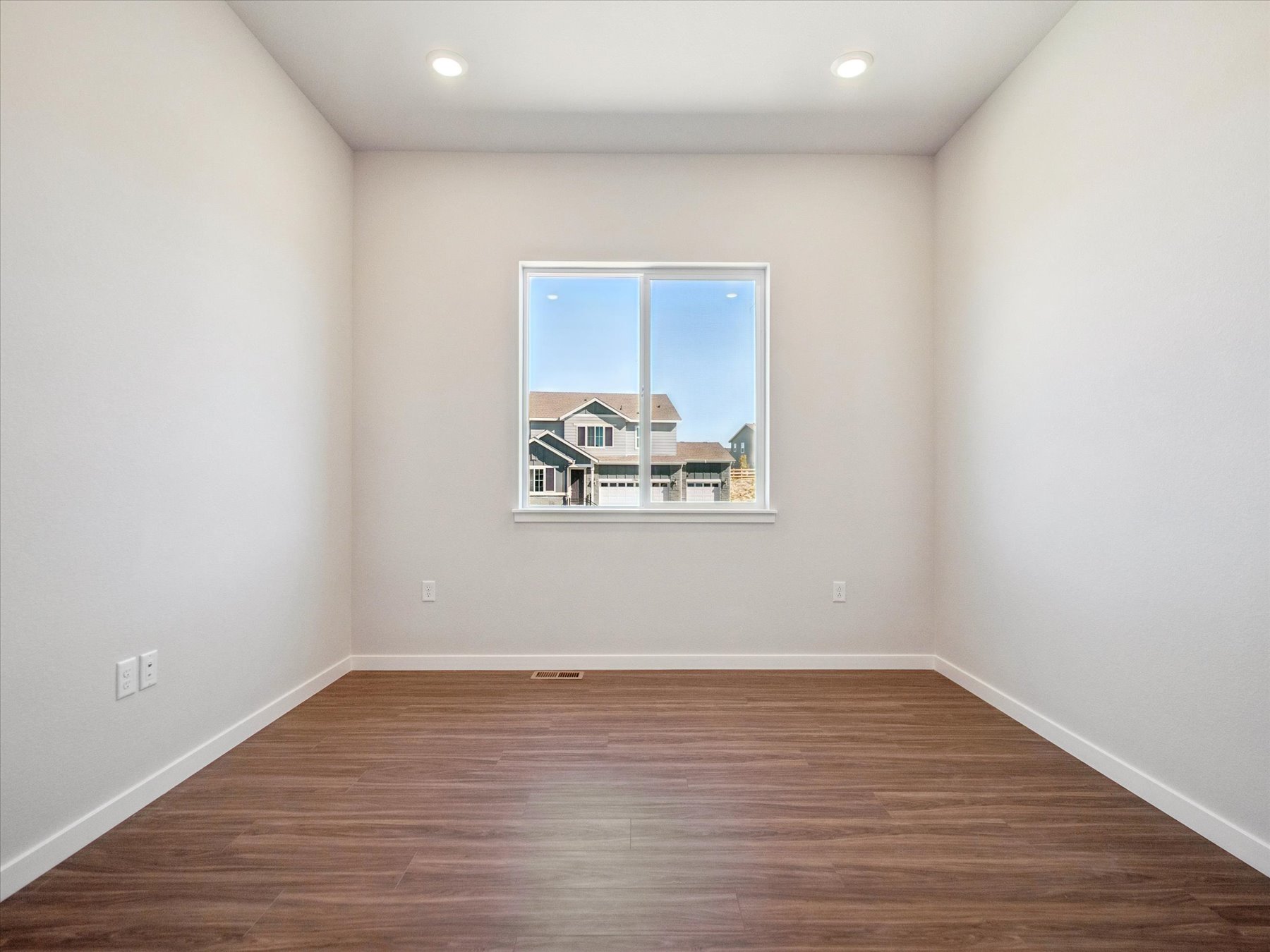 A room with a window and a wood floor.