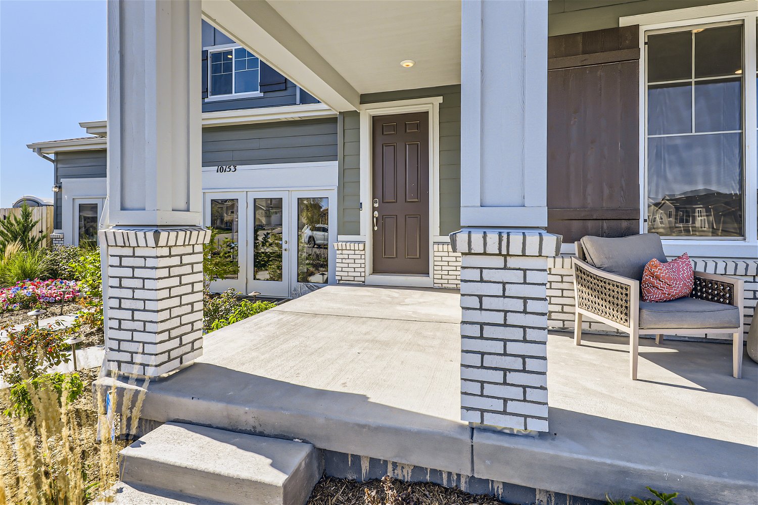 A patio with a chair and a fireplace in front of a house.