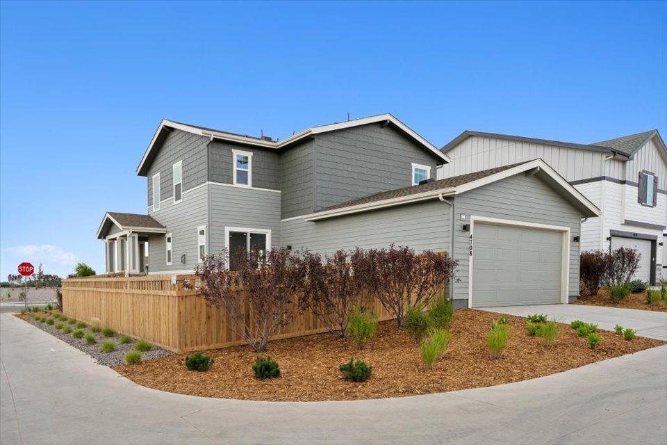 A house with a fence and bushes in front of it.