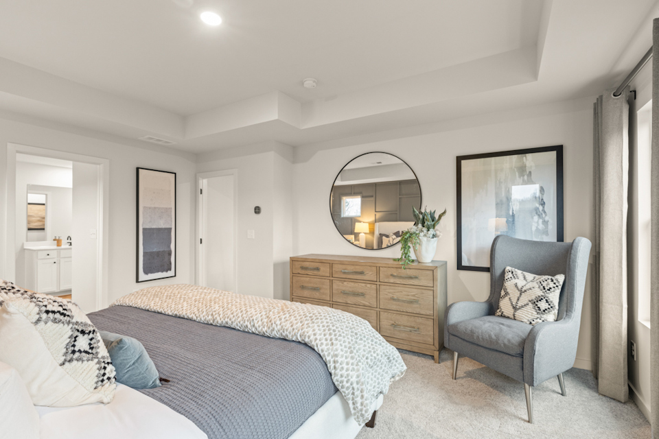 A bedroom with a bed and a chair.