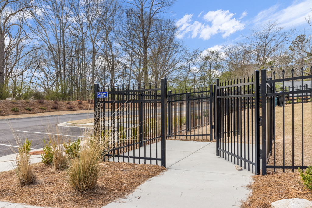 A gated off area with a road and trees in the background.