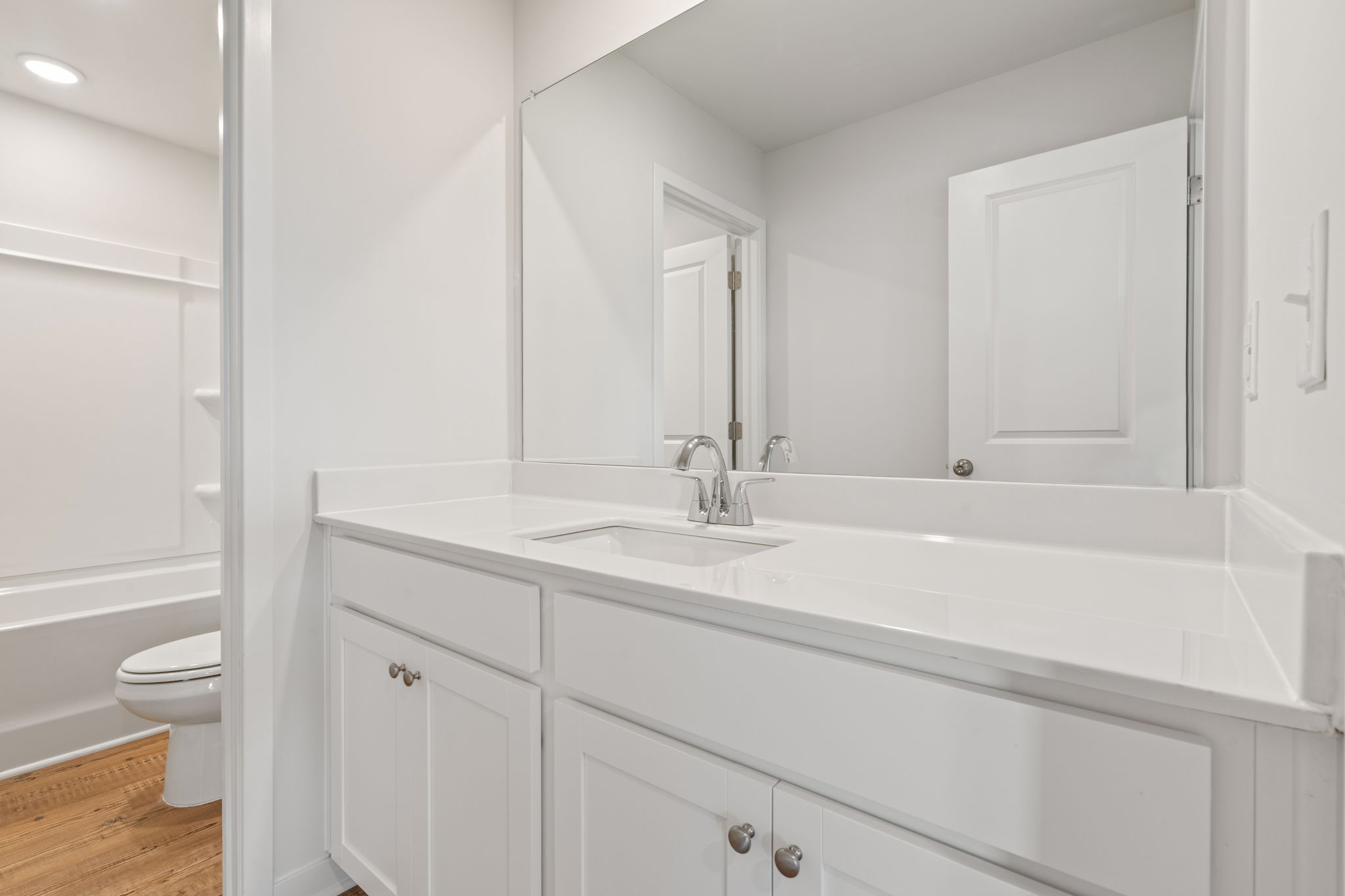 A bathroom with white cabinets.