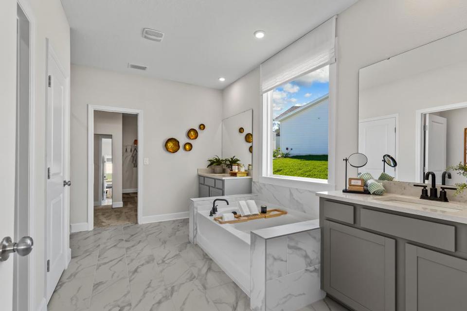 A bathroom with a tub sink and a large window.
