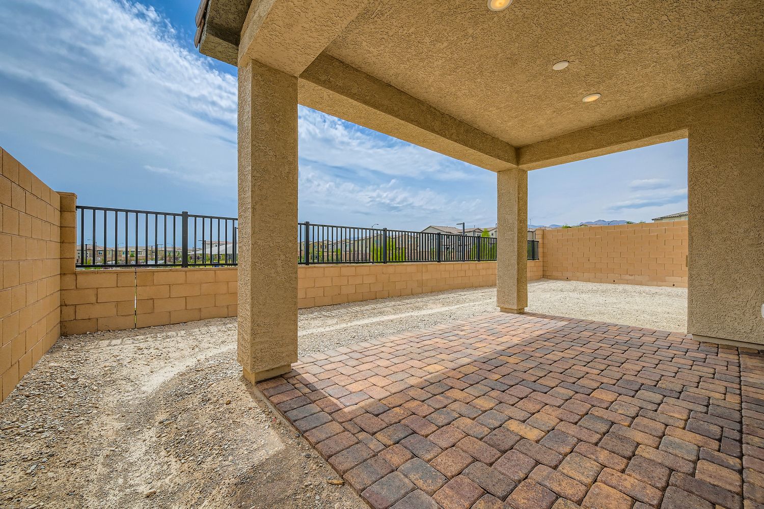 A stone walkway with a fence and a building in the background.