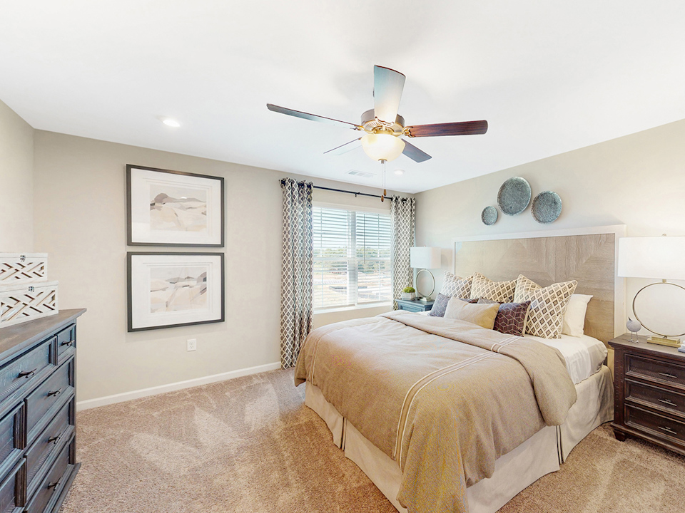 A bedroom with a bed and a fan.