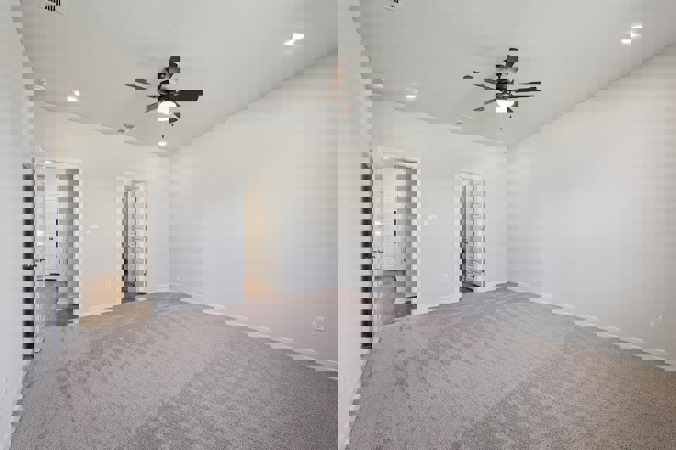 A room with a ceiling fan and a carpet.