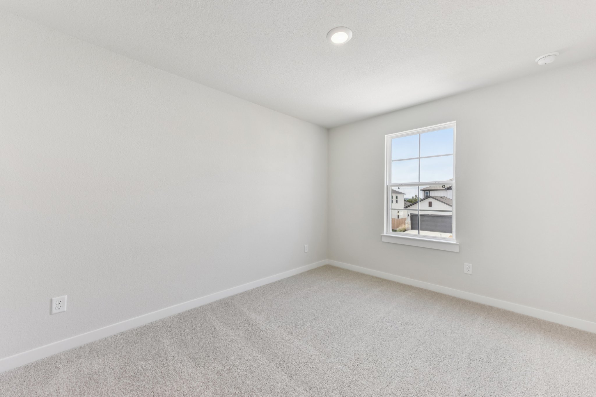 A room with a window and a light on the wall.