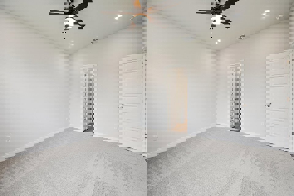 A room with a ceiling fan and a door.