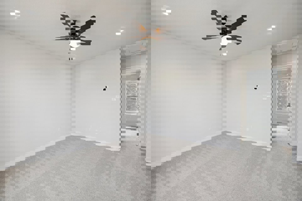 A room with a ceiling fan and a door.