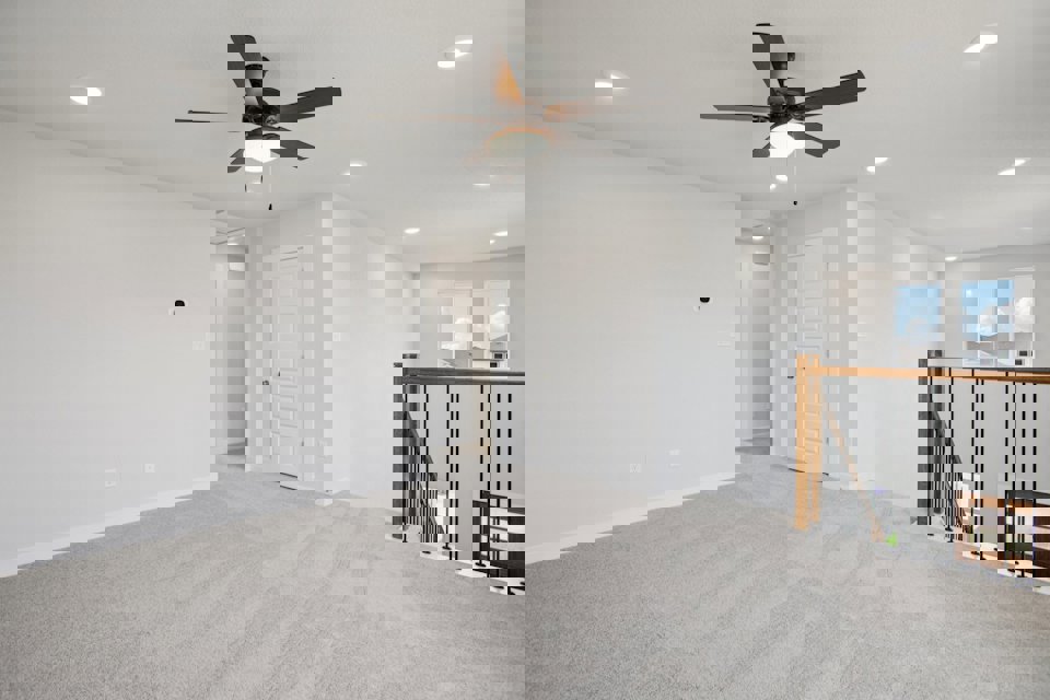 A room with a ceiling fan and a railing.