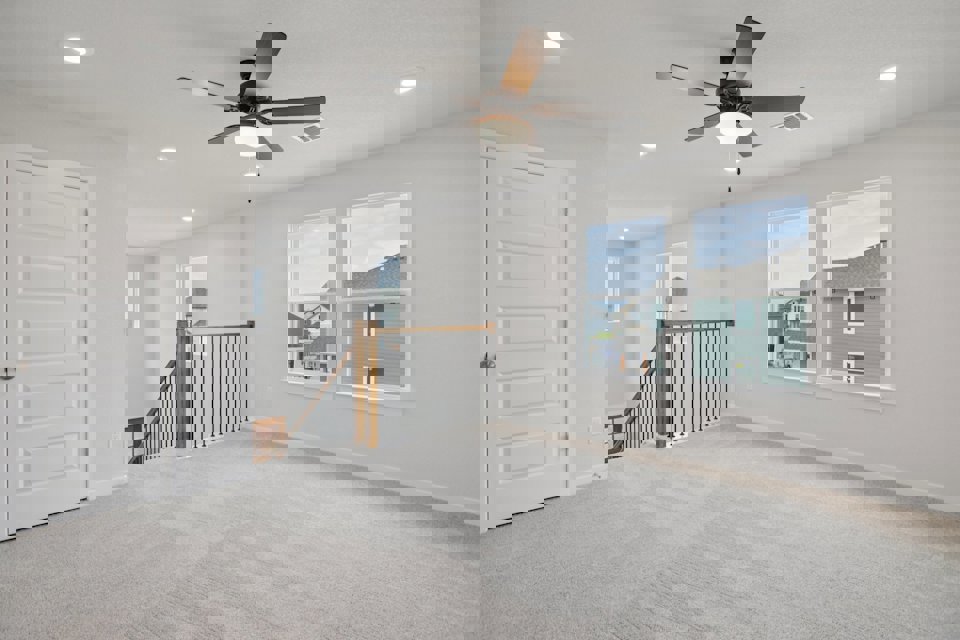 A room with a ceiling fan and a door with a window and a railing.