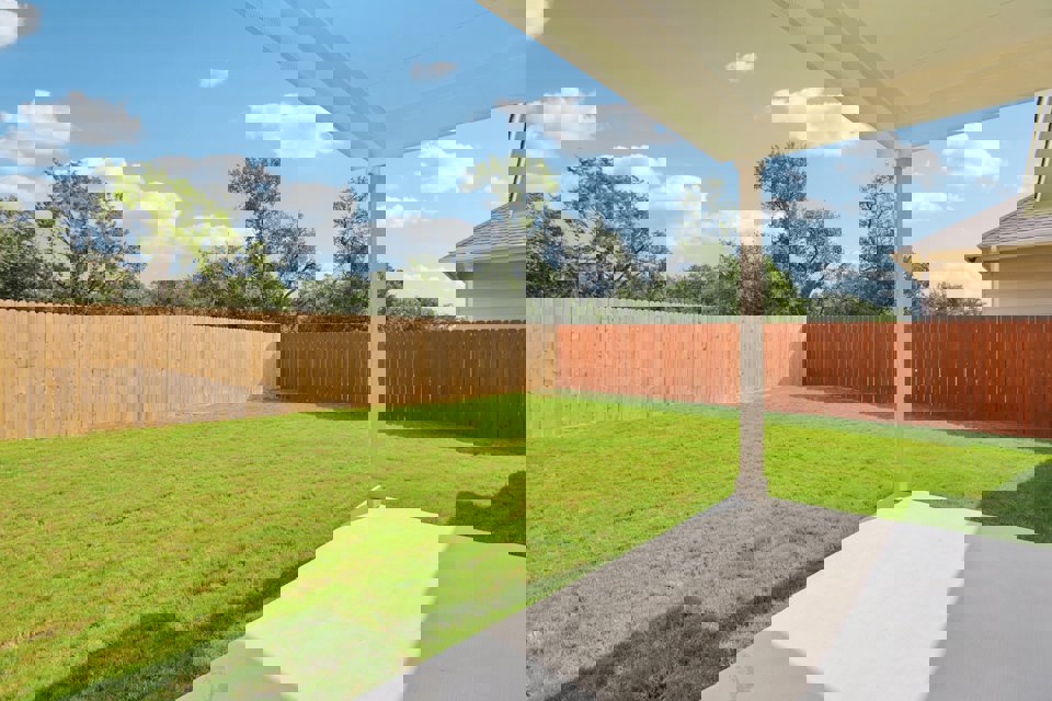 A backyard with a fence and a lawn.