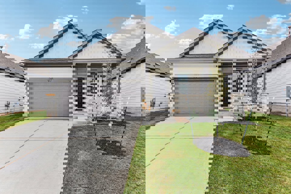 A house with a garage and a tree in the front.