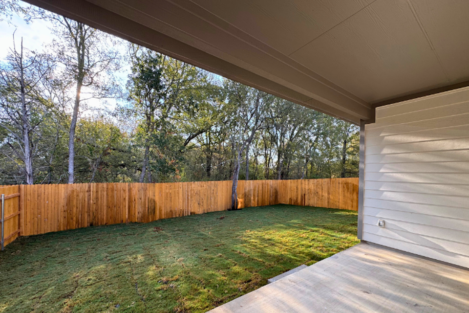 A wooden deck with a wood fence and trees in the background.
