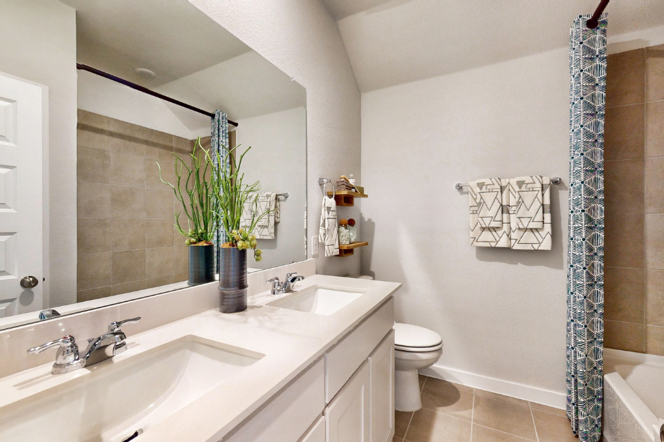 A bathroom with a sink toilet and a mirror.