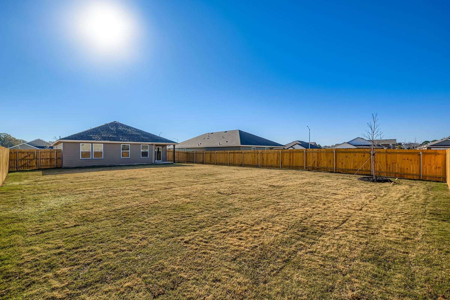 A field with a fence and buildings in the background.