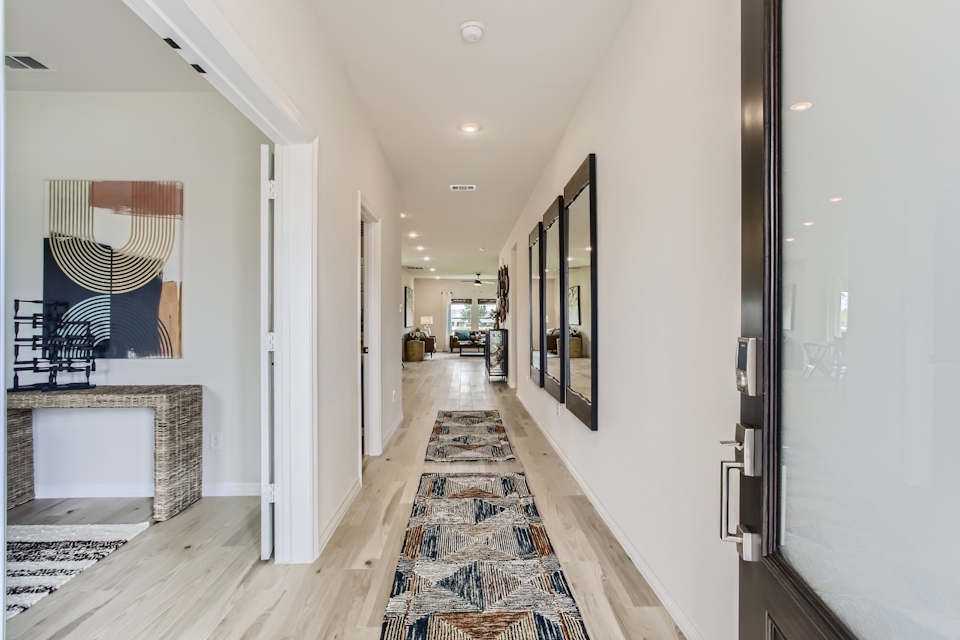 A hallway with a rug and a mirror.