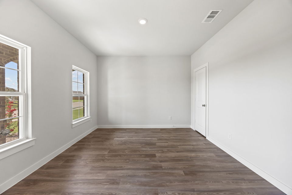 A room with a wood floor and windows.