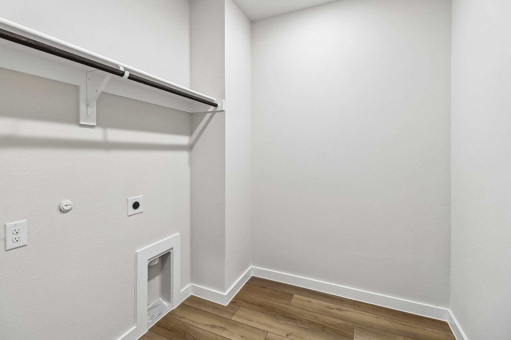 A white wall with a wood floor.