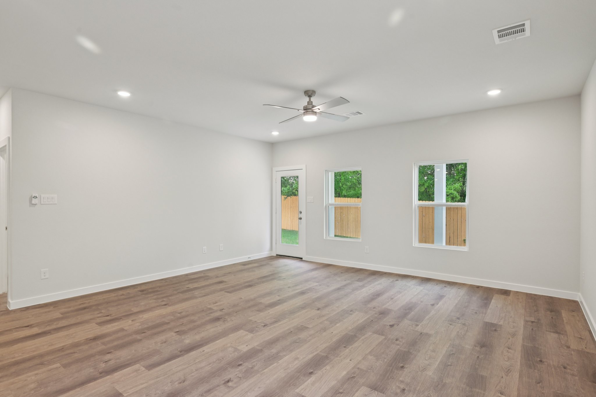 A room with a wood floor and a ceiling fan.