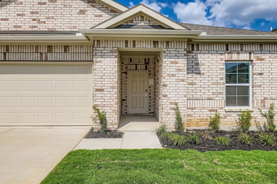 A house with a garage and a lawn in front of it.