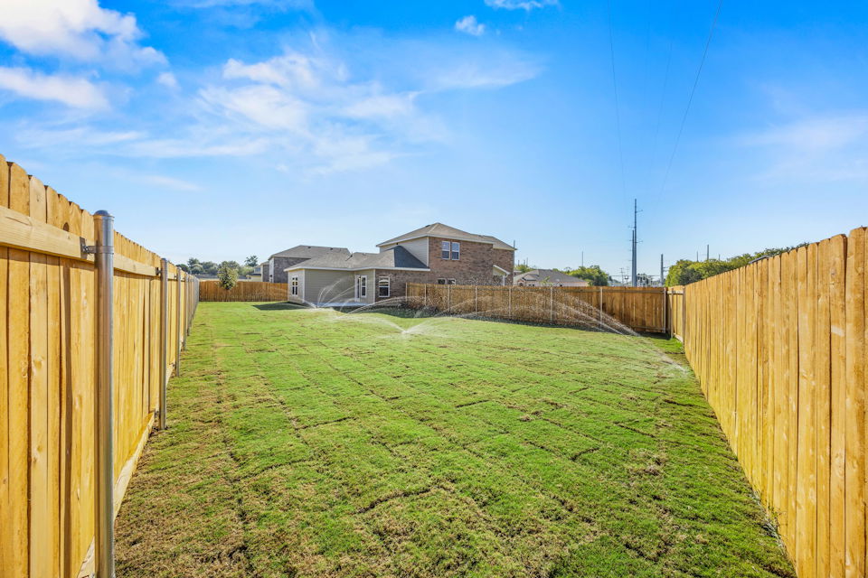 A fenced in yard with a house in the background.