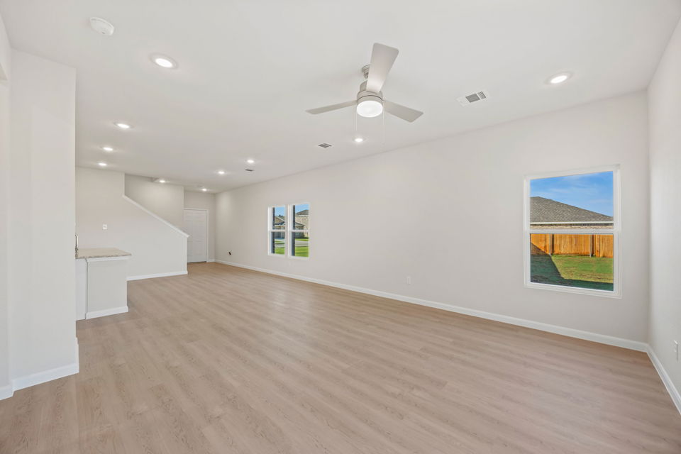 A large room with a wood floor and a ceiling fan.