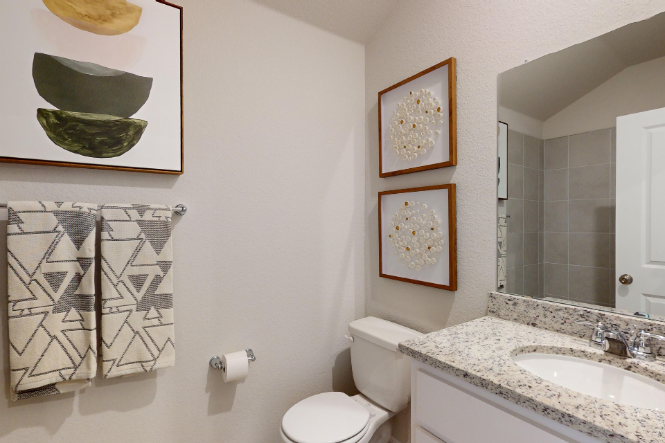 A bathroom with a sink toilet and a mirror.
