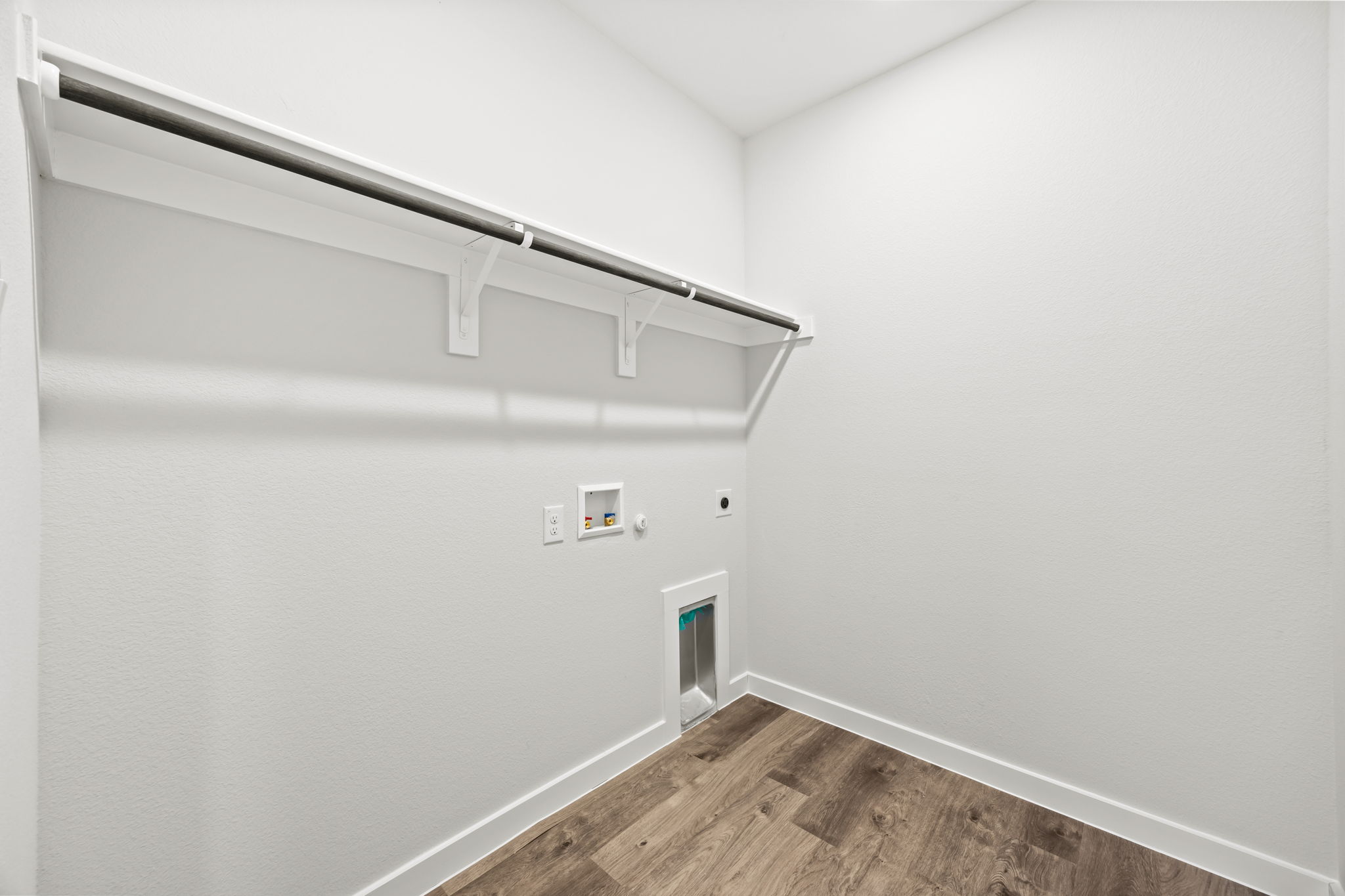 A white wall with a wood floor.