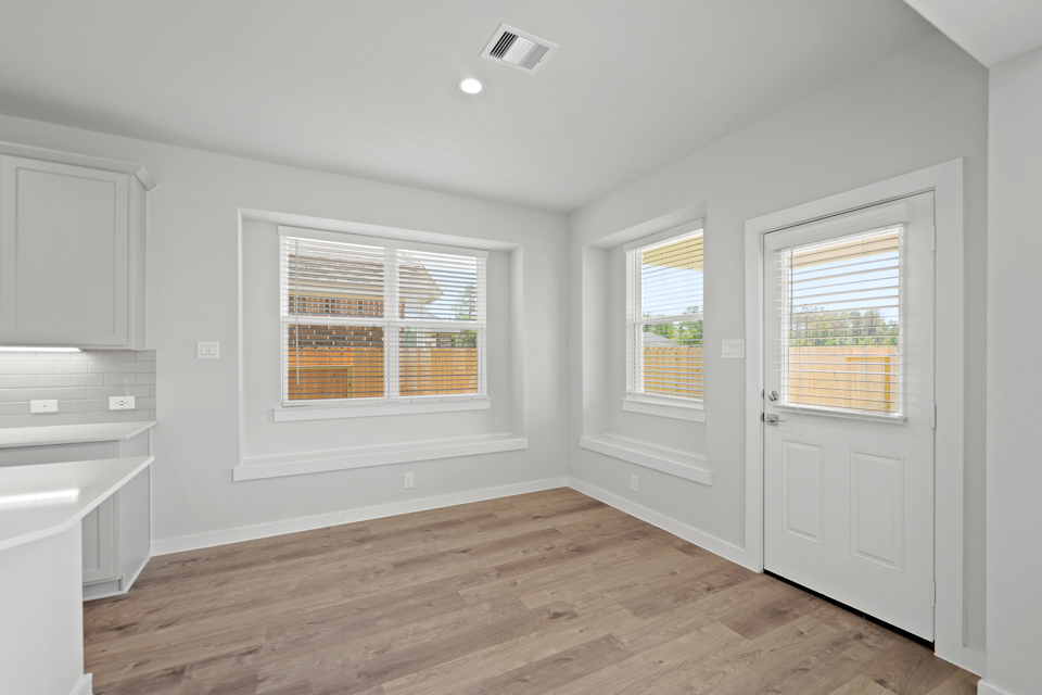 A room with white cabinets and a wood floor.