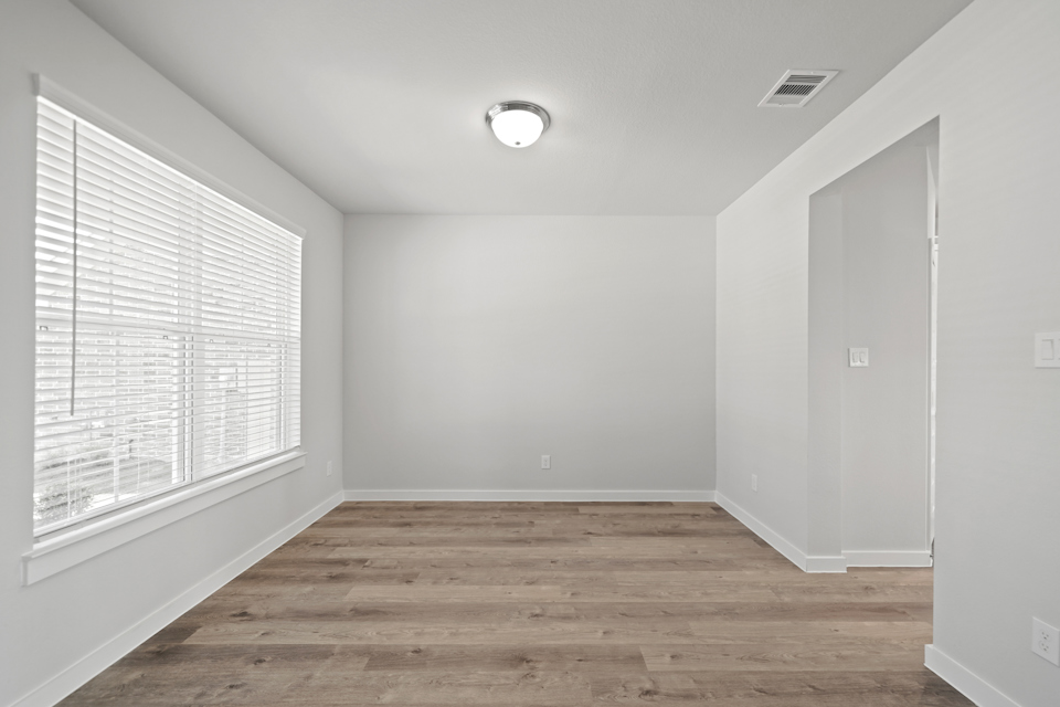 A room with a wood floor and a white wall with a light.
