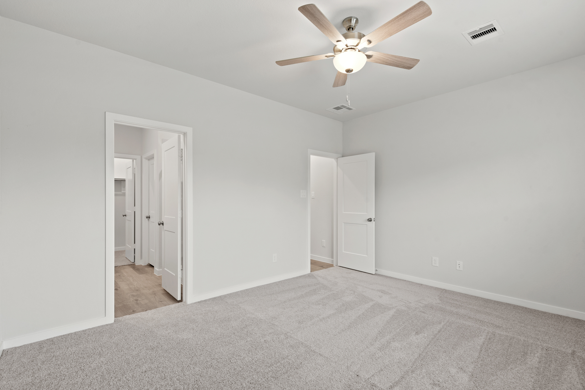 A room with a ceiling fan and white doors.