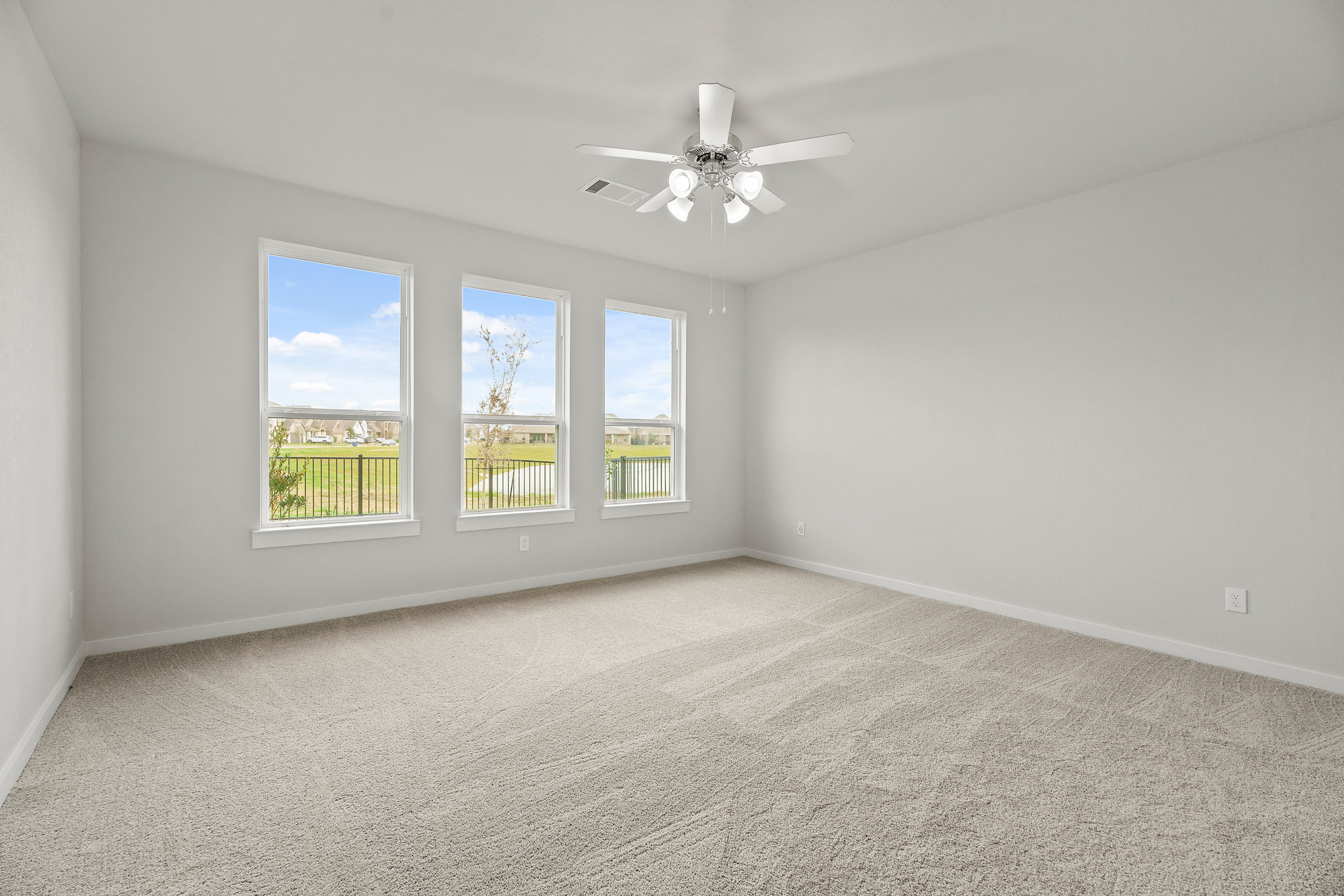 A room with a ceiling fan and a window with a view of the ocean.