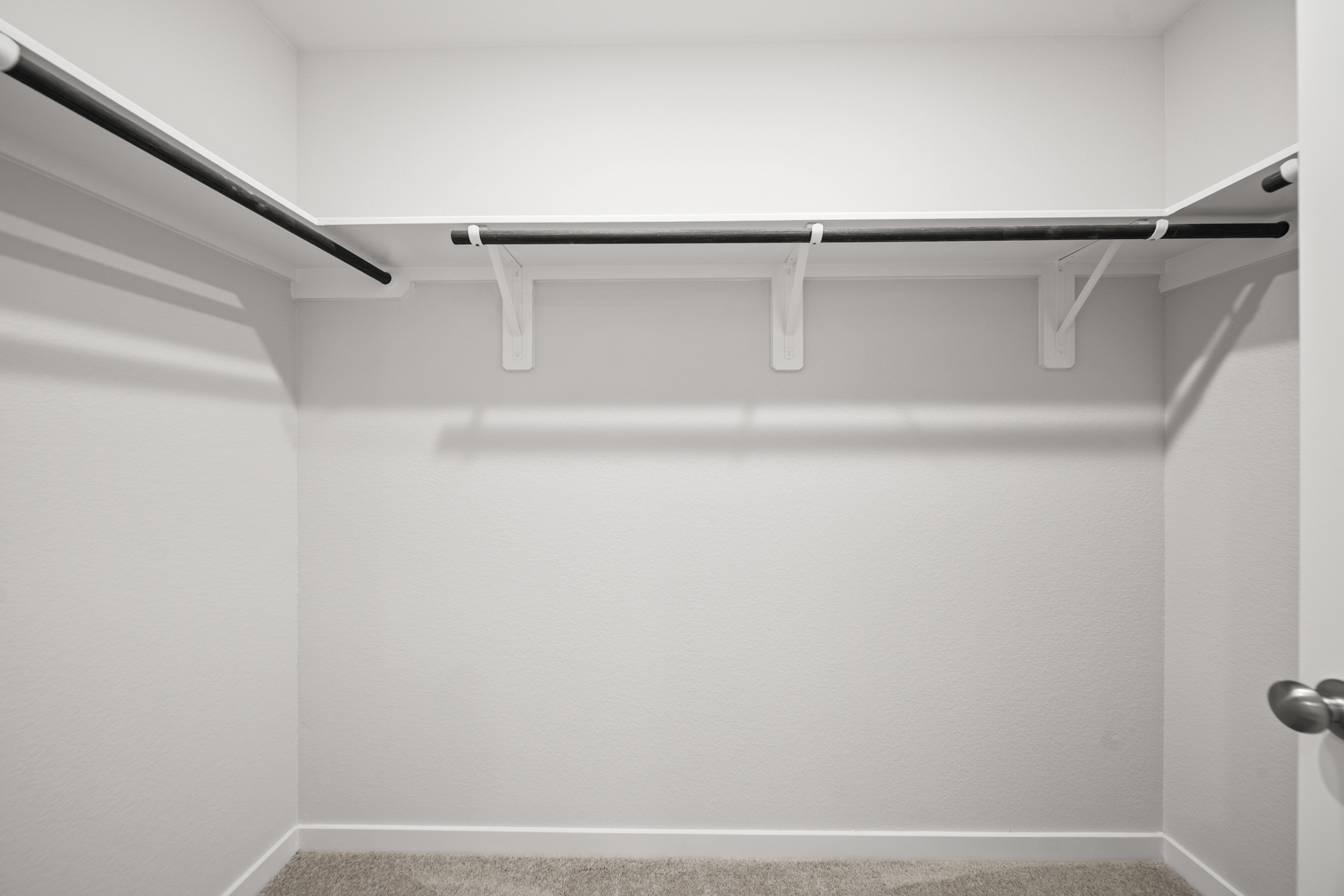 A white wall with a metal bar.