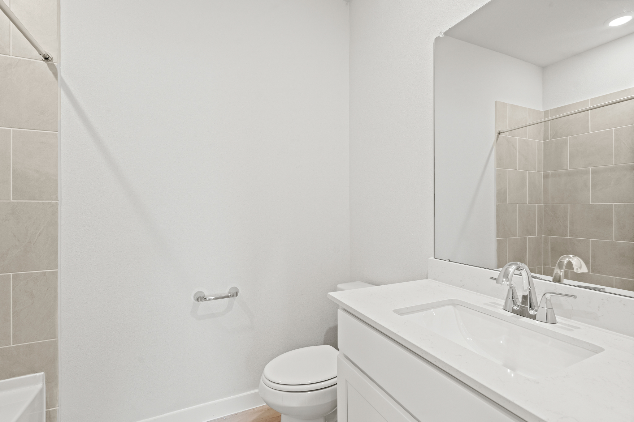 A bathroom with a sink toilet and mirror.