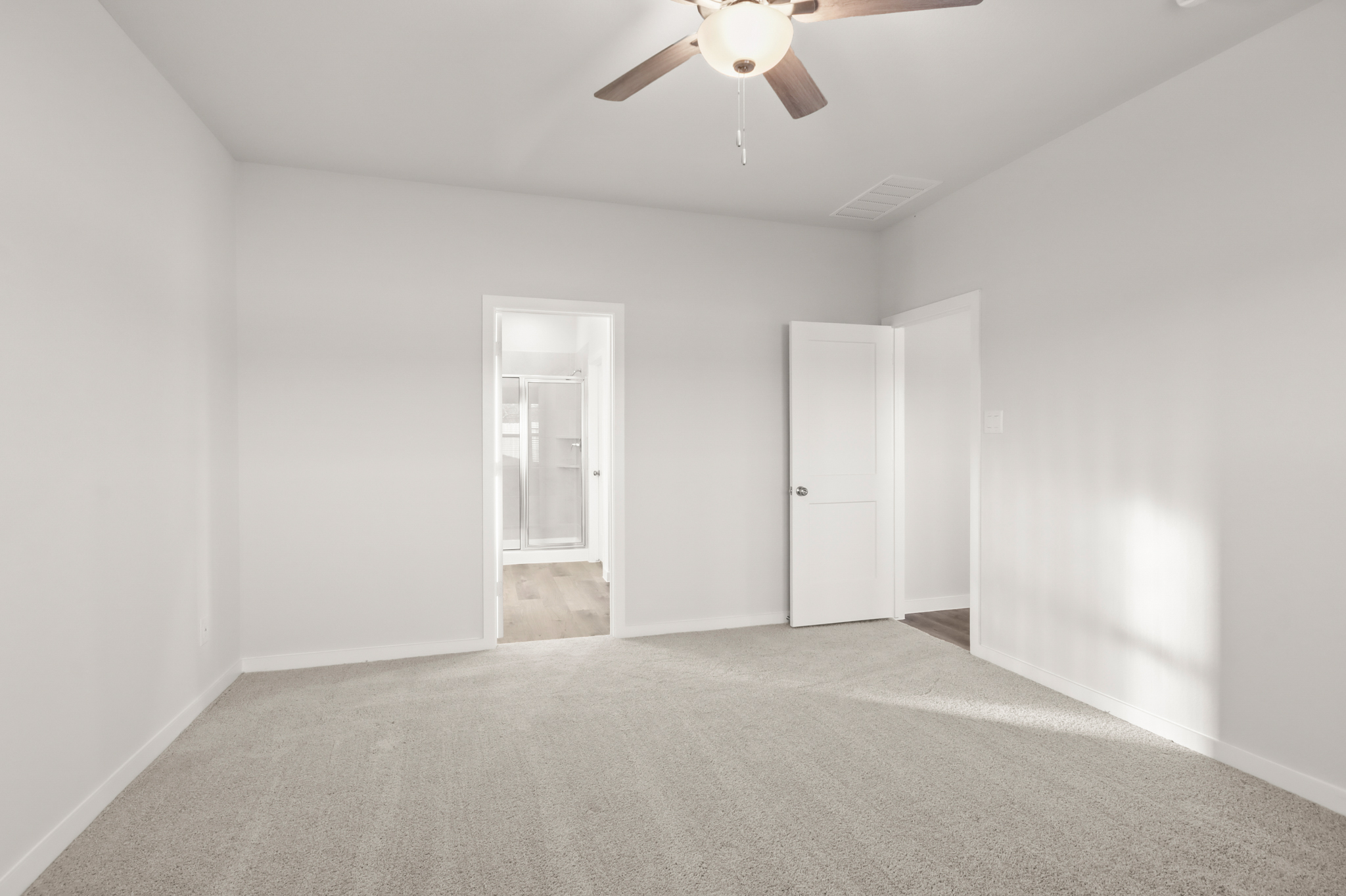 A room with a ceiling fan and a carpet.