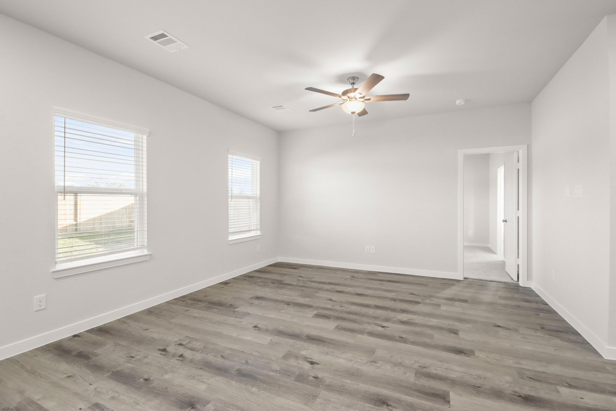 A room with a wood floor and a ceiling fan.